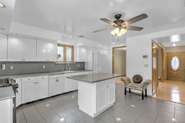 kitchen with sink, light tile patterned floors, white appliances, a center island, and white cabinets