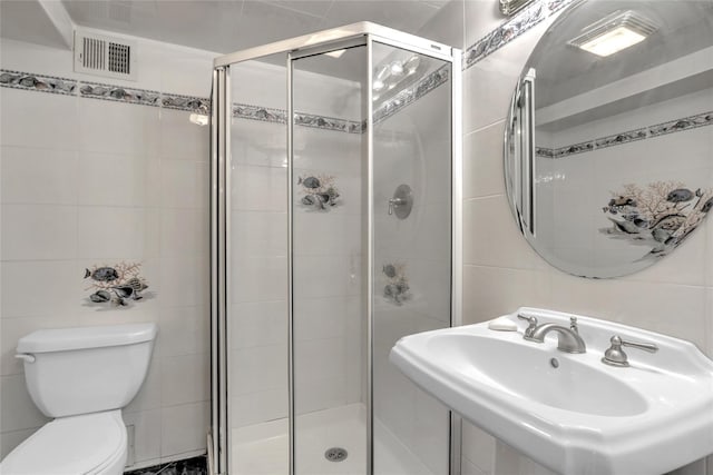 bathroom featuring a shower with door, sink, tile walls, and toilet