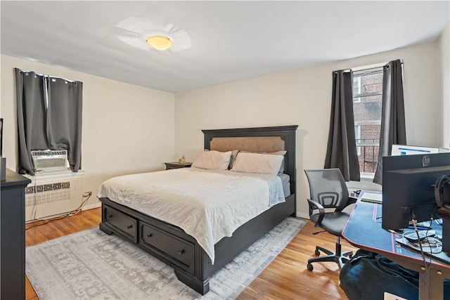 bedroom with wood-type flooring, radiator heating unit, and cooling unit