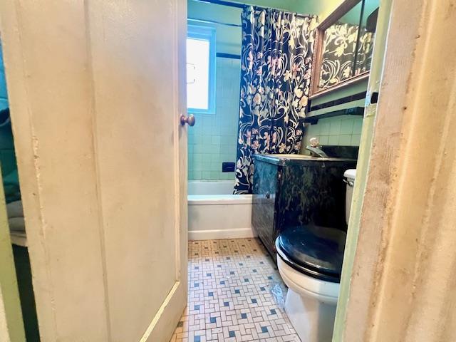 full bathroom with shower / bathtub combination with curtain, sink, backsplash, and toilet