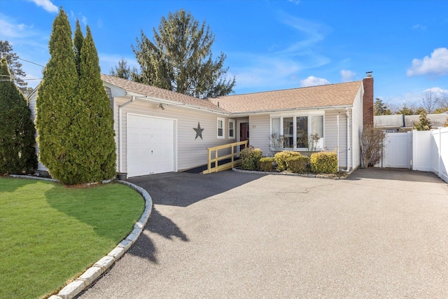 single story home featuring a front yard, fence, a chimney, a garage, and aphalt driveway