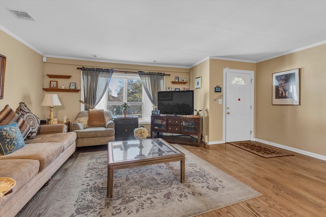 living room featuring visible vents, baseboards, wood finished floors, and crown molding