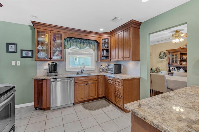 kitchen featuring visible vents, light stone counters, brown cabinets, appliances with stainless steel finishes, and a sink