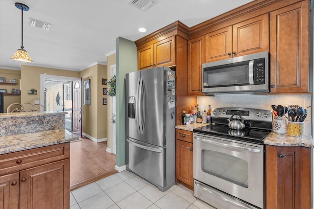 kitchen with brown cabinets, light tile patterned floors, visible vents, and stainless steel appliances