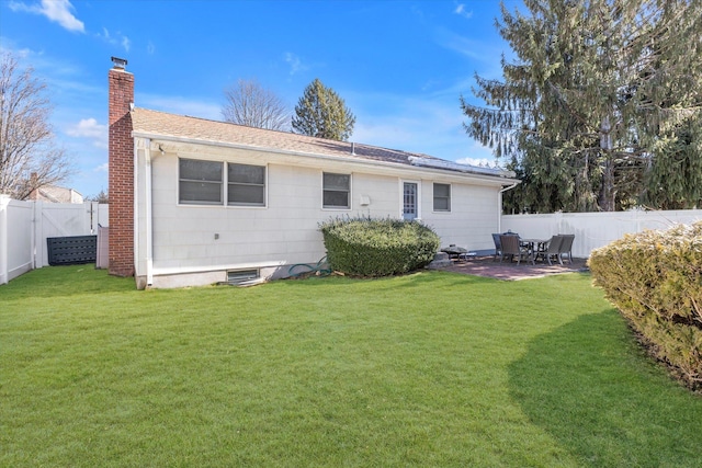 rear view of property featuring a patio area, a yard, a fenced backyard, and a chimney