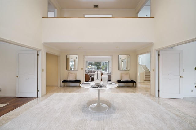 entryway featuring crown molding, a towering ceiling, visible vents, and stairs