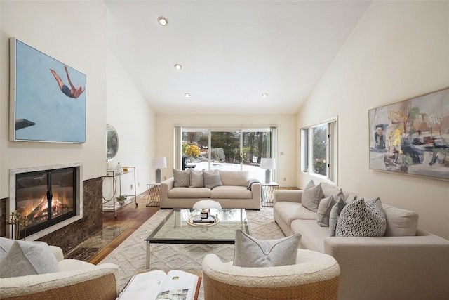 living room with recessed lighting, high vaulted ceiling, a premium fireplace, and wood finished floors