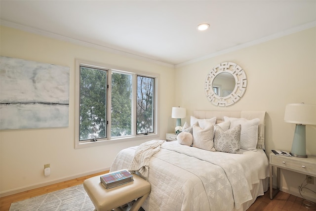 bedroom featuring baseboards, crown molding, and wood finished floors