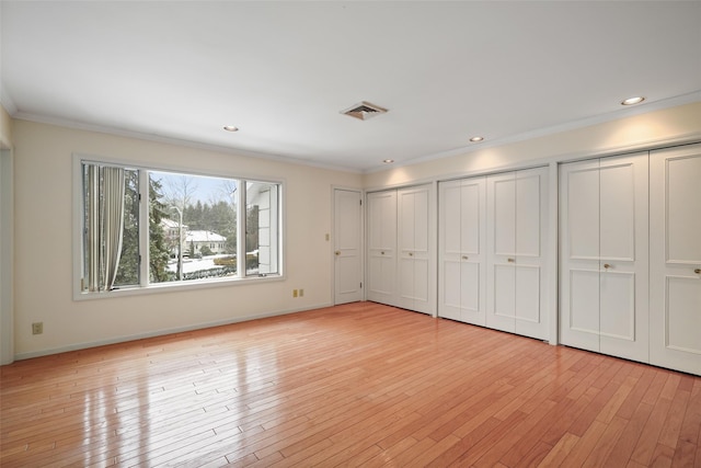 unfurnished bedroom with light wood-style flooring, ornamental molding, multiple closets, and recessed lighting