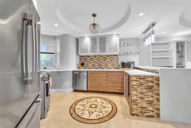 kitchen with pendant lighting, appliances with stainless steel finishes, a raised ceiling, and light tile patterned floors