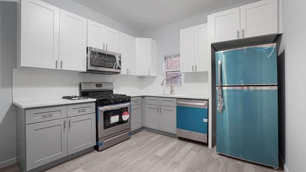 kitchen featuring sink, appliances with stainless steel finishes, white cabinets, and gray cabinetry