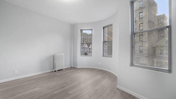 unfurnished room featuring hardwood / wood-style flooring and radiator