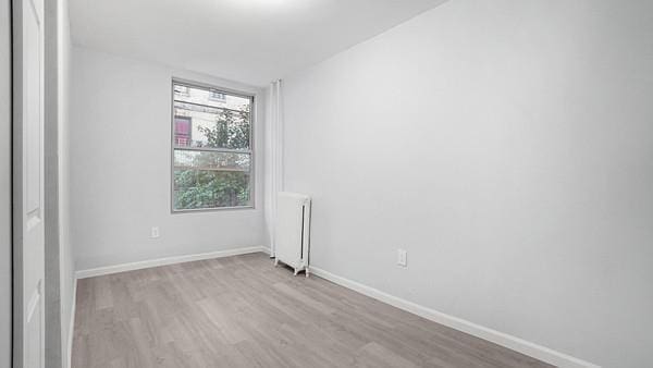 empty room featuring radiator and light hardwood / wood-style flooring