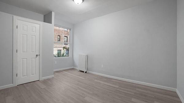 unfurnished bedroom featuring light wood-type flooring and radiator heating unit