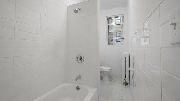 bathroom with radiator, tile walls, tiled shower / bath combo, and toilet