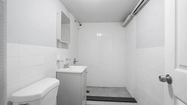 bathroom featuring tile walls, vanity, a tile shower, and toilet