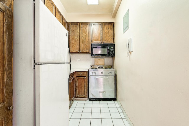 70-25 Yellowstone Blvd Unit 18A, Forest Hills, NY 11375 - kitchen featuring black microwave, freestanding refrigerator, stainless steel gas range oven, brown cabinetry, and light tile patterned floors