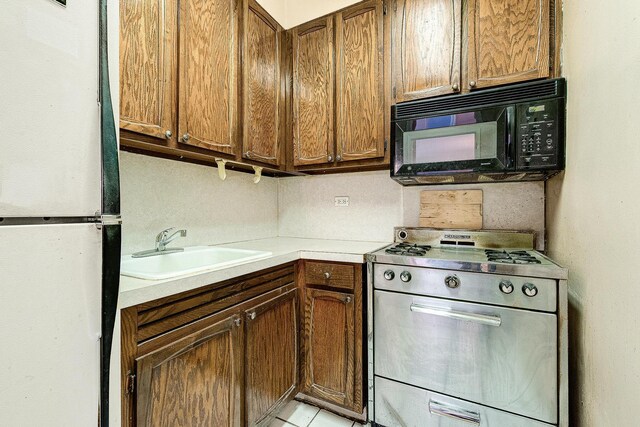 70-25 Yellowstone Blvd Unit 18A, Forest Hills, NY 11375 - kitchen with stainless steel gas range oven, black microwave, a sink, freestanding refrigerator, and light countertops