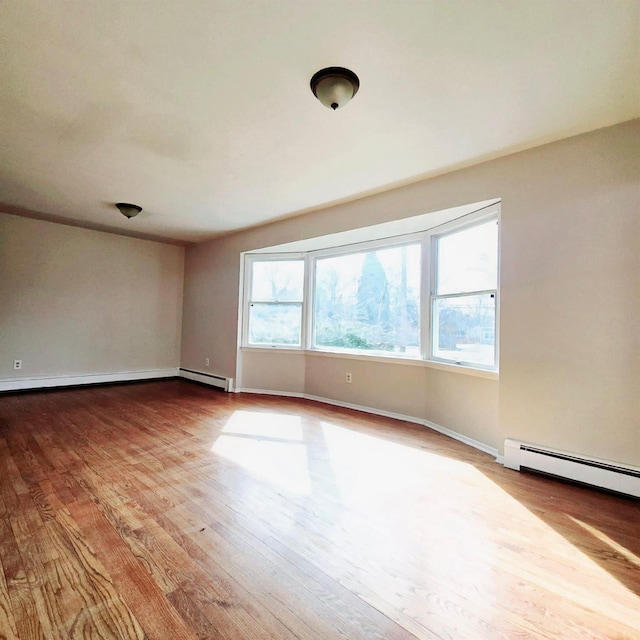 empty room featuring a baseboard heating unit and light hardwood / wood-style flooring