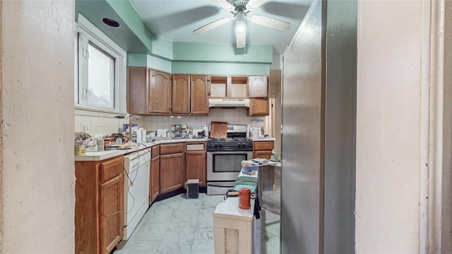 kitchen with under cabinet range hood, light countertops, marble finish floor, stainless steel gas stove, and dishwasher