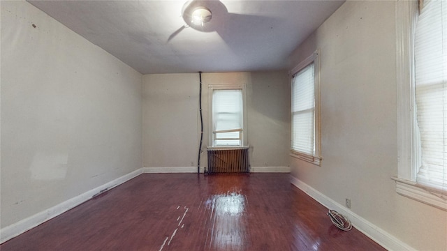 unfurnished room featuring ceiling fan, radiator heating unit, baseboards, and dark wood finished floors