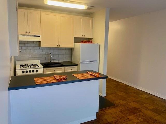 kitchen with sink, stove, white cabinetry, decorative backsplash, and white fridge