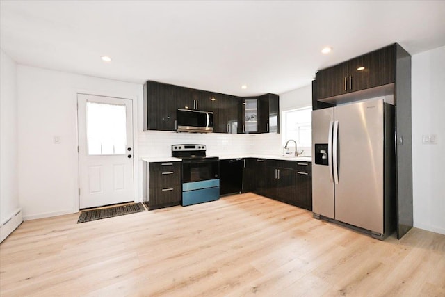 kitchen with sink, stainless steel appliances, tasteful backsplash, dark brown cabinetry, and light wood-type flooring