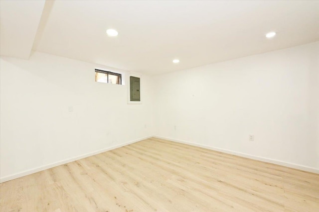 basement with electric panel and light hardwood / wood-style flooring