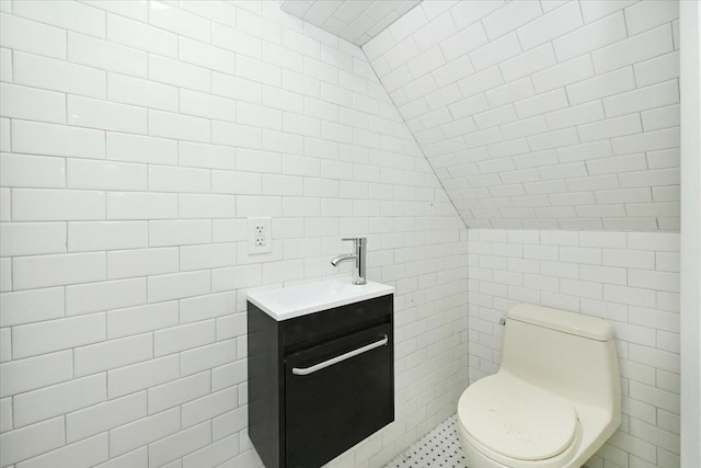 bathroom with vanity, lofted ceiling, toilet, and tile walls