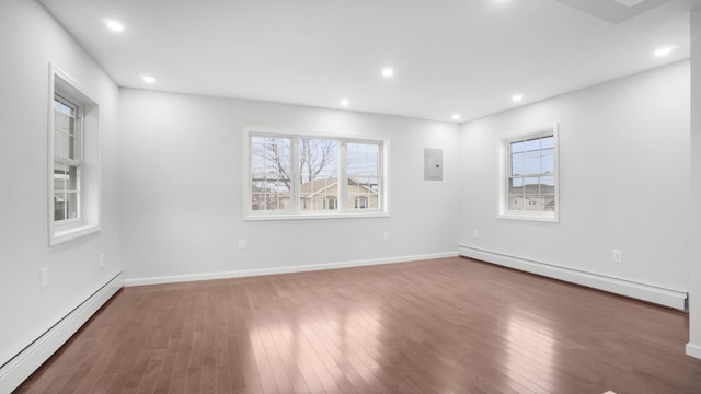 unfurnished room featuring a baseboard heating unit, dark hardwood / wood-style floors, and a healthy amount of sunlight