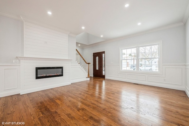 2101 Fir St, Wantagh, NY 11793 - unfurnished living room featuring a decorative wall, crown molding, a wainscoted wall, wood finished floors, and a large fireplace