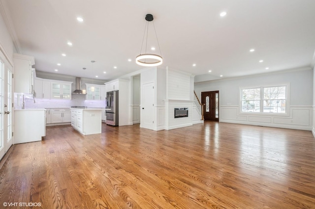 2101 Fir St, Wantagh, NY 11793 - unfurnished living room featuring crown molding, light wood finished floors, a large fireplace, a decorative wall, and wainscoting