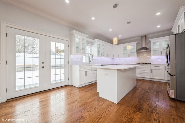 2101 Fir St, Wantagh, NY 11793 - kitchen featuring freestanding refrigerator, wall chimney exhaust hood, crown molding, a center island, and white cabinets