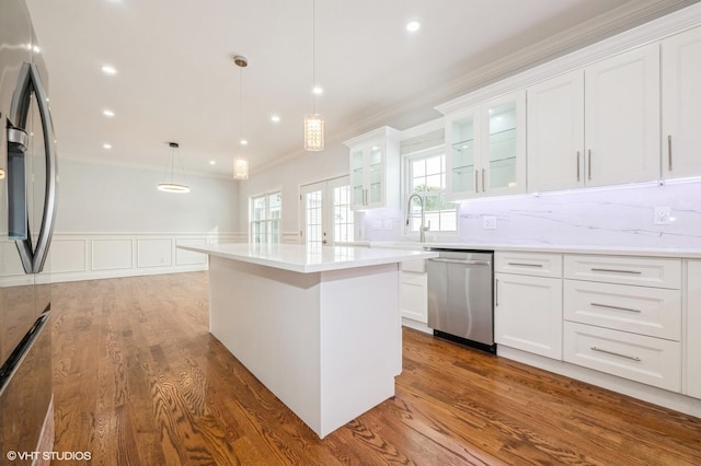 2101 Fir St, Wantagh, NY 11793 - kitchen featuring appliances with stainless steel finishes, crown molding, white cabinets, a center island, and a wainscoted wall