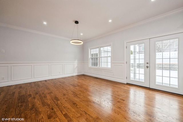 2101 Fir St, Wantagh, NY 11793 - unfurnished dining area with crown molding, wainscoting, wood finished floors, french doors, and a decorative wall