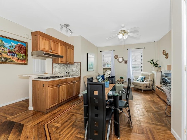 91 E 208th St Unit 3K, Bronx, NY 10467 - kitchen featuring brown cabinets, decorative backsplash, ceiling fan, light countertops, and under cabinet range hood