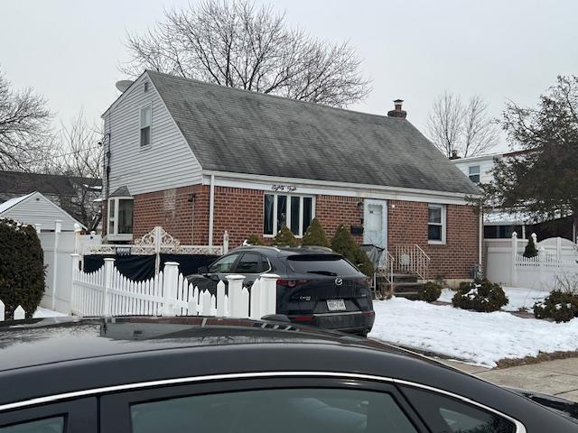 view of front of property with brick siding, a chimney, and fence