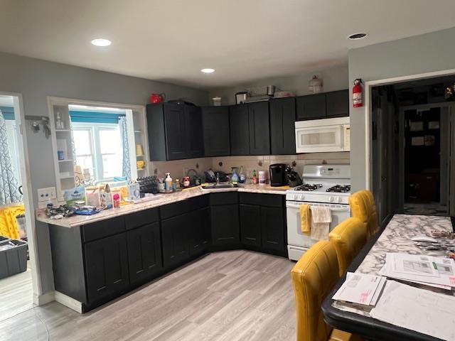 kitchen with white appliances, light countertops, and dark cabinetry