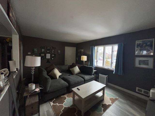 living room featuring visible vents, baseboards, and wood finished floors