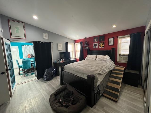 bedroom featuring lofted ceiling, light wood finished floors, access to outside, and multiple windows