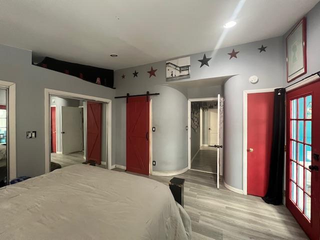 unfurnished bedroom with light wood-style floors, a barn door, and baseboards