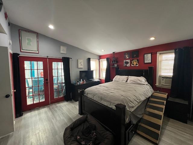 bedroom featuring lofted ceiling, multiple windows, light wood-type flooring, and cooling unit