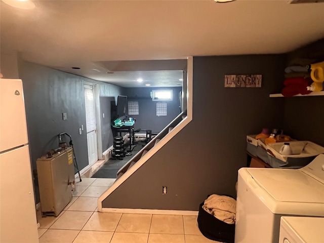 clothes washing area with independent washer and dryer, laundry area, light tile patterned flooring, and baseboards