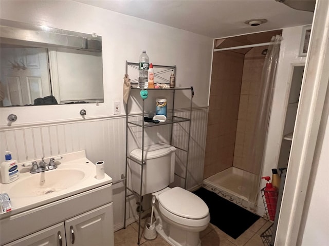 bathroom featuring wainscoting, toilet, a shower stall, and vanity