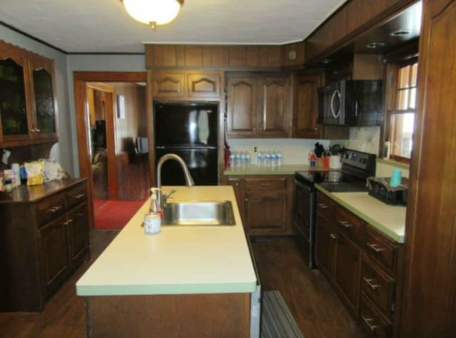 kitchen featuring sink, electric range, a center island with sink, dark hardwood / wood-style flooring, and black fridge