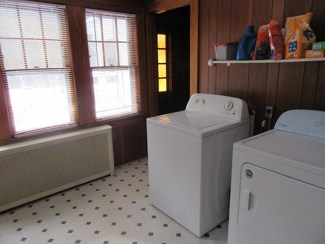 laundry area with washing machine and dryer, radiator, and a wealth of natural light