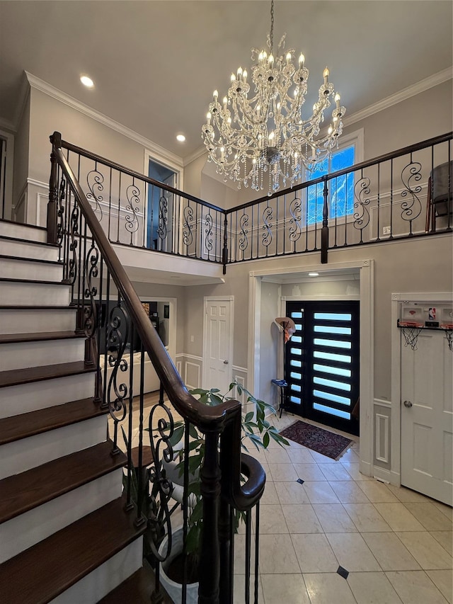 foyer entrance with ornamental molding, light tile patterned floors, an inviting chandelier, and stairs