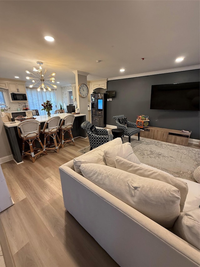 living room featuring a chandelier, light wood-type flooring, and crown molding