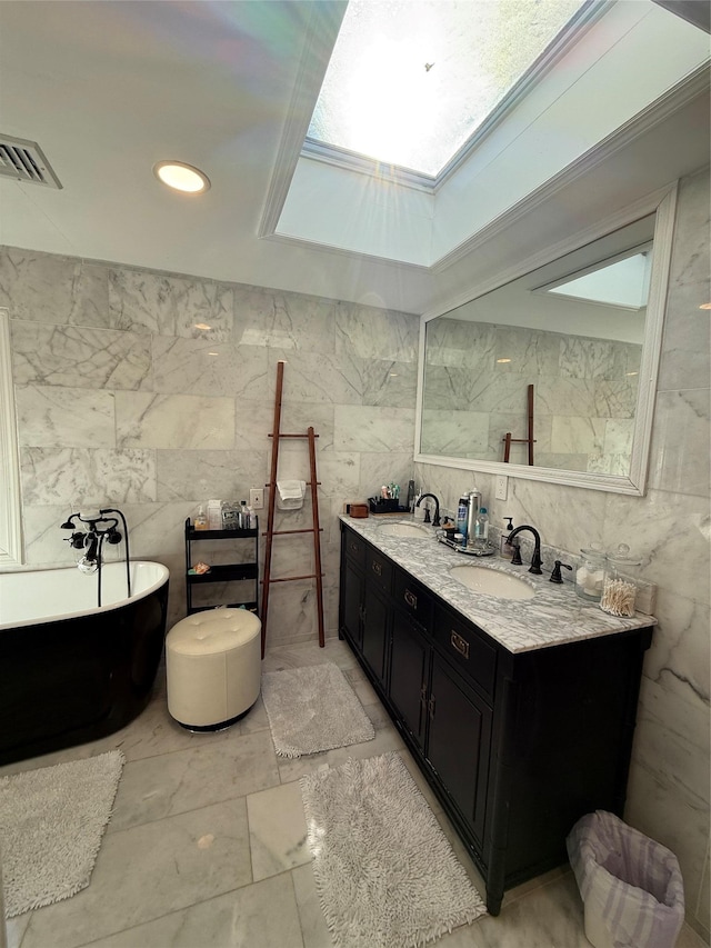 bathroom with double vanity, visible vents, a sink, a freestanding tub, and tile walls