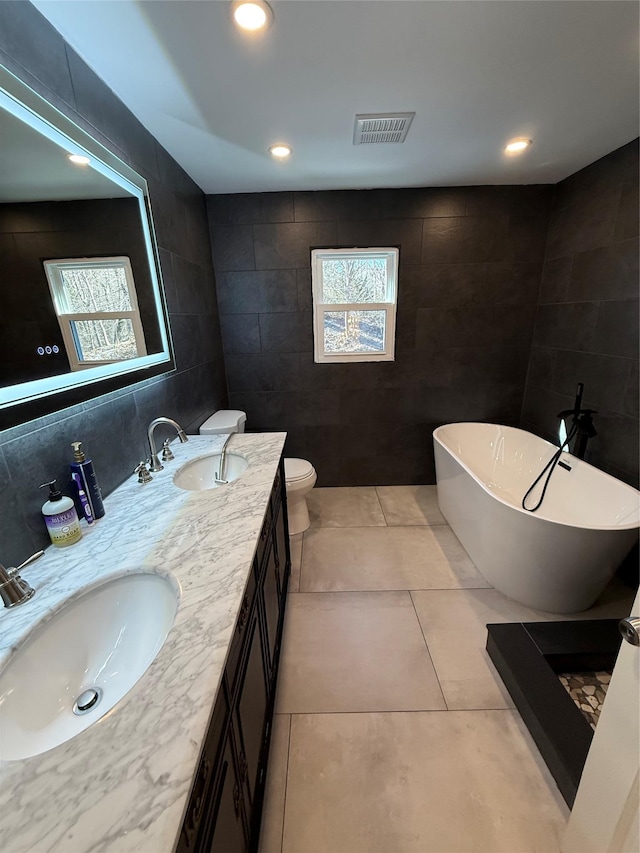 full bath with visible vents, a sink, and tile walls